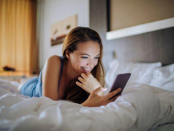 Woman laying in bed and using a smartphone 